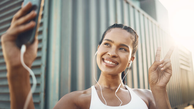 Fitness, selfie or happy woman in city with peace sign listening to music or radio in sports exercise. Mobile photography, smile or girl athlete runner taking pictures in training workout outdoors