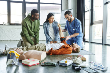 medical instructor applying compression tourniquet on arm of seminar participant near asian woman,...