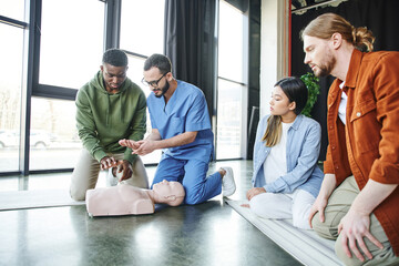 medical instructor explaining african american man cardiopulmonary resuscitation techniques near...