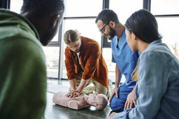 cardiopulmonary resuscitation, young man doing chest compressions on CPR manikin during hands-on...