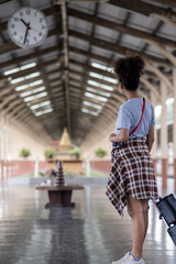Young female traveler walking standing with a suitcase at train station. woman traveler tourist walking standing smiling with luggage at train station
