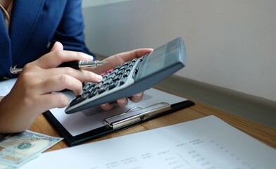 Business woman calculating financial statement on calculator income tax online return and payment