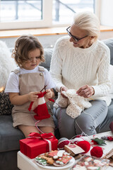Grandmother and granddaughter spend quality time together, knitting, preparing handmade decoration...