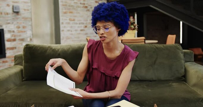 Biracial businesswoman with blue afro having video call in office, slow motion
