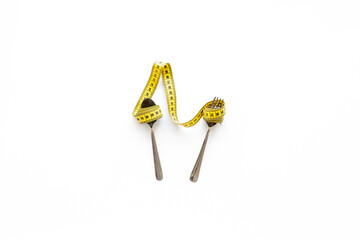 Yellow tape measure and cutlery. Diet and body weight control concept