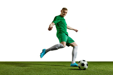 Dribbling. Young man, football player in green uniform in motion, training, playing against white background. Concept of professional sport, action, lifestyle, competition, hobby, training, ad