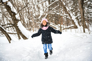 smiling american child during snowfall in winter park