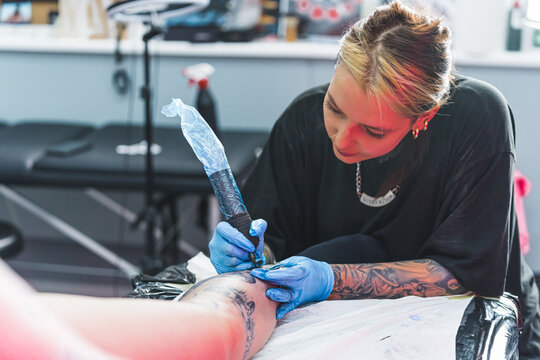 medium shot of a young tattoo master drawing a new tattoo with pleasure, tattoo artist concept. High quality photo