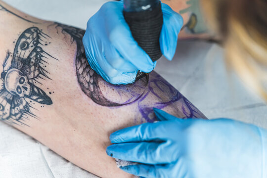 closeup shot of a tattoo master working on a new tattoo in the studio. High quality photo