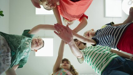 A successful team, the children together with the teacher put their hands on each other and joyfully rise to the top. At the beginning of the school, a happy smiling class, the team studies together. - Powered by Adobe