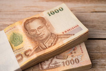 Stack of Thai baht banknotes on wooden background, business saving finance investment concept.