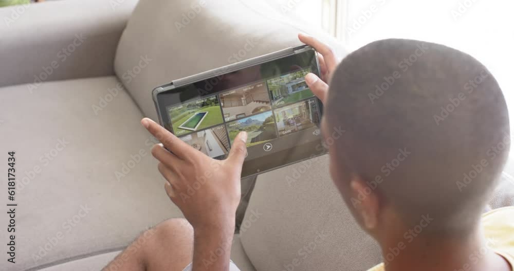 Poster biracial man using tablet with home security camera views on screen, slow motion