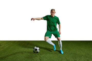 Obraz premium Concentrated young man, football player in green uniform dribbling ball, training against white background. Concept of professional sport, action, lifestyle, competition, hobby, training, ad