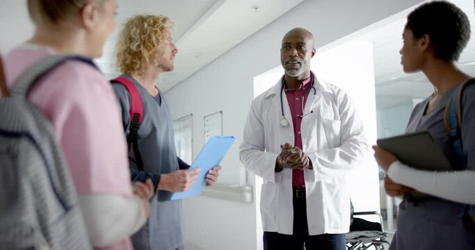 Diverse doctors discussing work in corridor at hospital, slow motion
