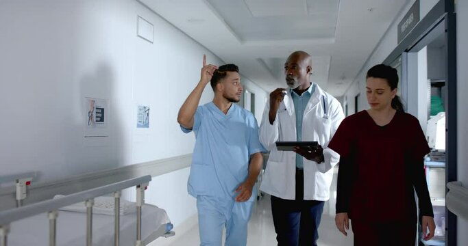 Diverse doctors discussing work and walking in corridor, slow motion