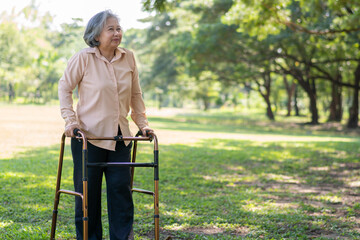 Happy old elderly Asian woman uses a walker for osteoarthritis rehabilitation physiotherapy in...
