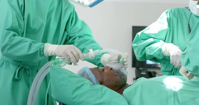 Diverse surgeons giving anesthesia to patient in operating theatre, slow motion