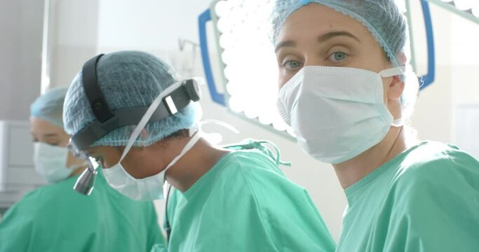 Portrait of caucasian female surgeon wearing face mask in operating theatre, slow motion