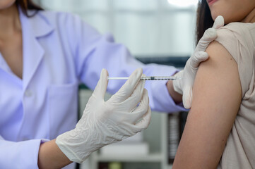 Closeup of doctor hand doing vaccination or injection on patient's shoulder Influenza vaccination...