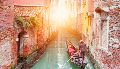 Venetian gondolier punting gondola through green canal waters of Venice Italy - obrazy, fototapety, plakaty