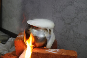 Milk is overflowing on a bricks stove due to excess boiling as a tradition in india for house...