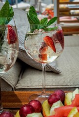 A refreshing summer drink served in a cocktail glass, garnished with fresh mint leaves, succulent strawberries, and a generous amount of ice.