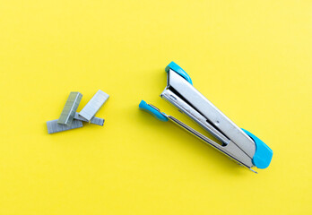 A stapler and its supplies isolated on yellow background, after some edits.
