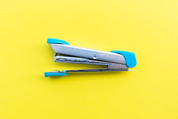 A stapler and its supplies isolated on yellow background, after some edits.