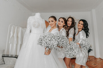 The bride's friends together with the bride hold bouquets of gypsophila flowers near the wedding...