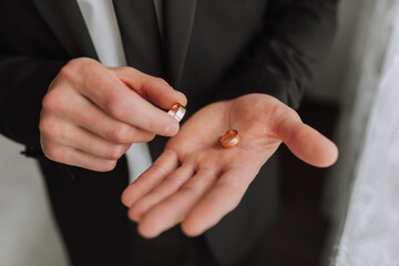 Obraz premium portrait of a man's manly hands holding golden wedding rings. The groom is preparing for the wedding ceremony.