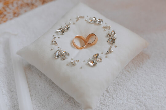 gold wedding rings on a cushion decorated in a circle with silver jewelry stones, preparation for the painting ceremony