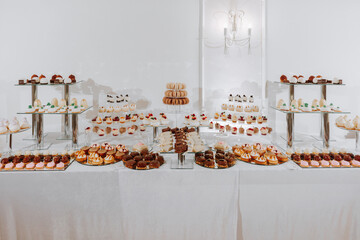 Festive dessert table with sweets. Wedding candy bar, various cakes, chocolates on stands.