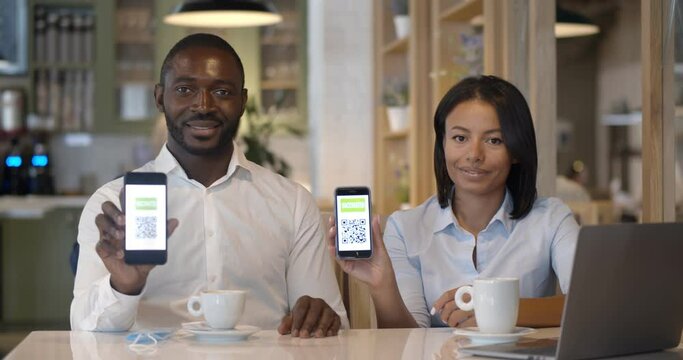 Portrait of business colleagues in restaurant showing vaccinated qr-code on smartphone at camera