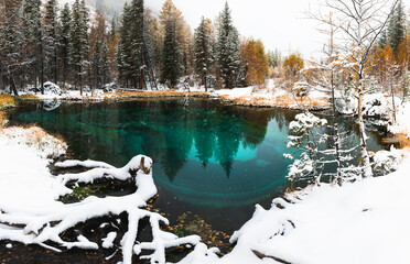 Blue geyser lake in autumn forest during snowfall. Altai, Siberia, Russia.