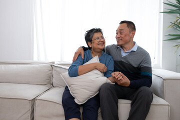 Senior couple sitting on sofa and looking each other.