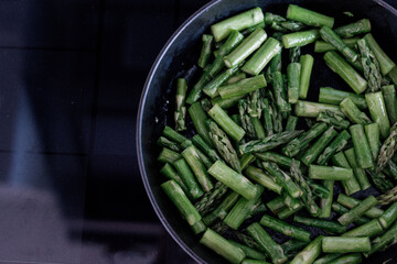 stir fried green asparagus in a cast iron pan
