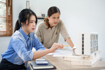 Fototapeta premium Concept of engineering consulting, Two female engineers discussing about model of building together