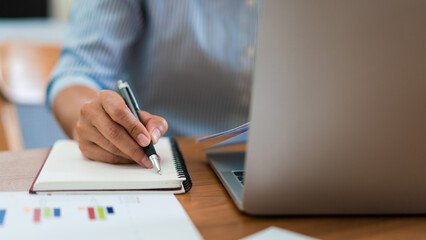 Close up hands of businesswoman working and reading business document to writing notes in notebook