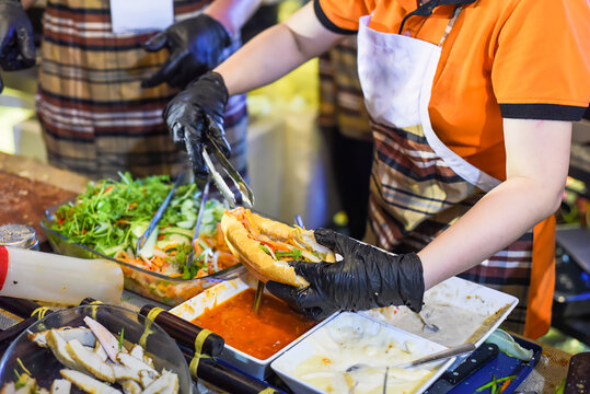 Vietnamese woman serving traditional vietnamese sandwich banh mi in street food at night