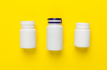 Plastic bottles with vitamins on color background, top view