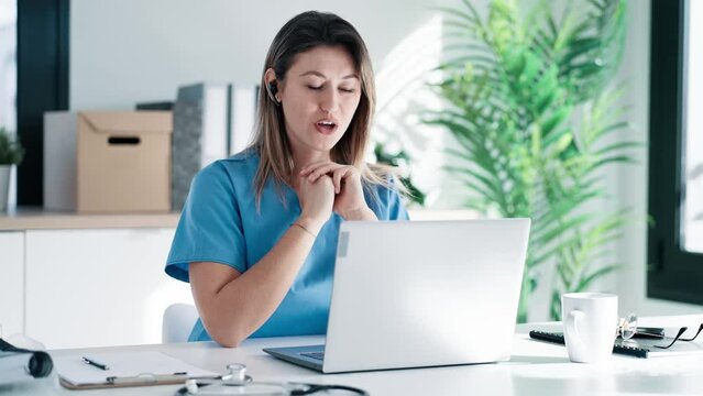 Video of female doctor talking with colleagues through a video call with a laptop in the consultation.
