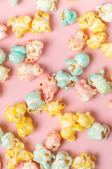 Fototapeta na wymiar Flavored sugary popcorn scattered on the pink surface as food background