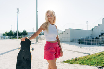 Beautiful stylish woman with her longboard in the park.