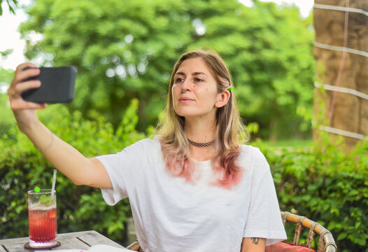 Cute woman taking a photo selfie and drinking tea in summer garden
