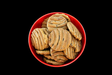 Top View Of Chocolate Chip Cookies Or Biscuits On Red Bowl. Isolated On Black Background. Selective Focus. Copy Space On Both Side