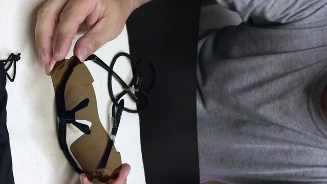 A man demonstrates removable colored lenses for sunglasses. Glasses with interchangeable colored lenses. A blogger makes a review of sunglasses. vertical video.