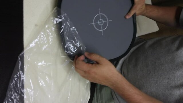 A man is packing a package. Gray card for setting the white balance when shooting. Puts in a case. vertical video.