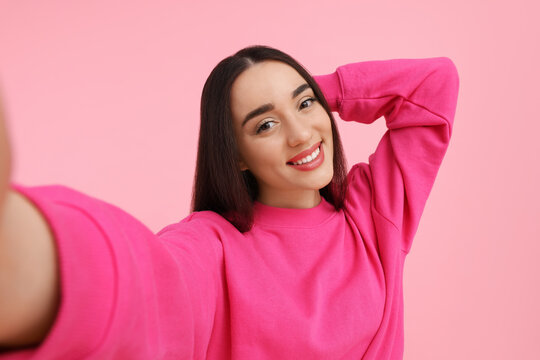 Smiling Young Woman Taking Selfie On Pink Background