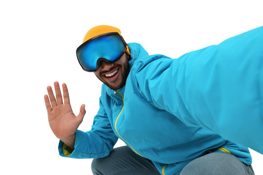 Smiling young man in ski goggles taking selfie on white background