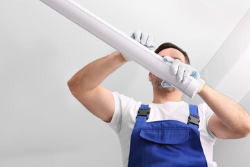 Ceiling light. Electrician installing led linear lamp indoors, low angle view. Space for text